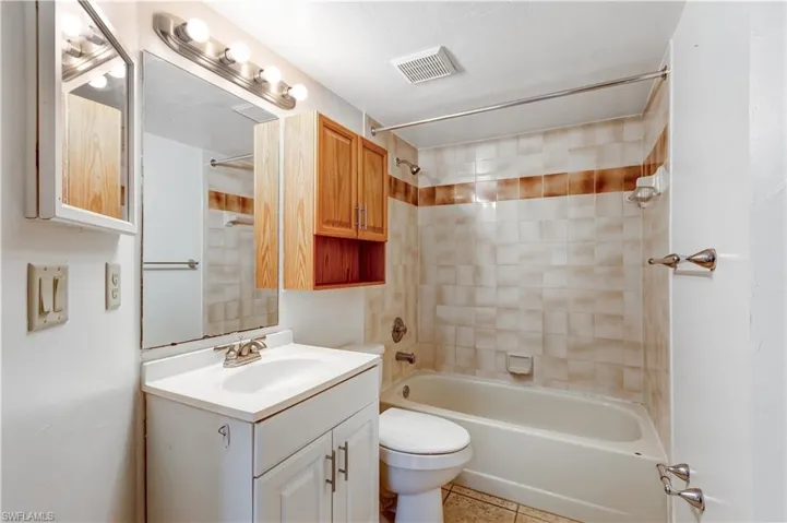 Full bathroom featuring vanity, toilet, tile patterned floors, and tiled shower / bath combo