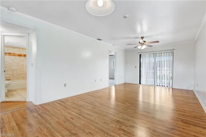 Unfurnished room with ornamental molding, light wood-type flooring, and ceiling fan