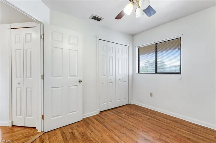 Unfurnished bedroom with two closets, light wood-type flooring, and ceiling fan