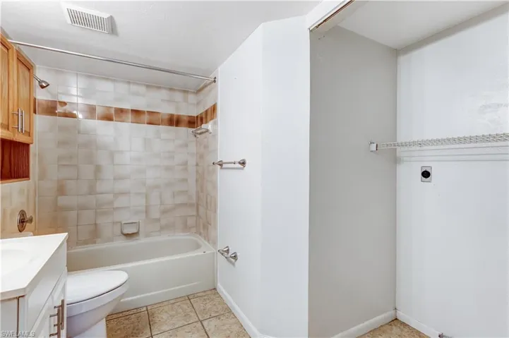 Full bathroom featuring toilet, tiled shower / bath combo, vanity, and tile patterned floors