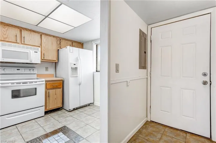 Kitchen featuring electric panel, white appliances, and light tile patterned floors