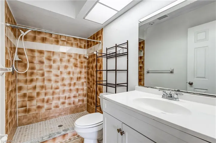 Bathroom with vanity, toilet, tile patterned floors, and a tile shower