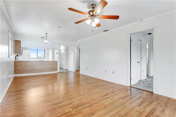 Unfurnished living room featuring crown molding, light hardwood / wood-style floors, and ceiling fan