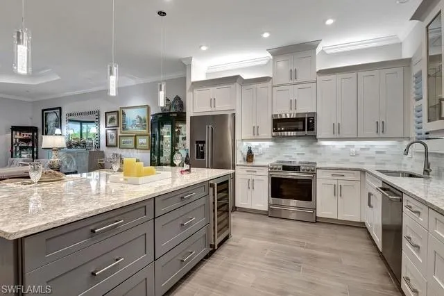 featuring wine cooler, decorative backsplash, Cambria Quartz  counters, upgraded stainless steel appliances, lower sized gray cabs with additional storage and pull outs