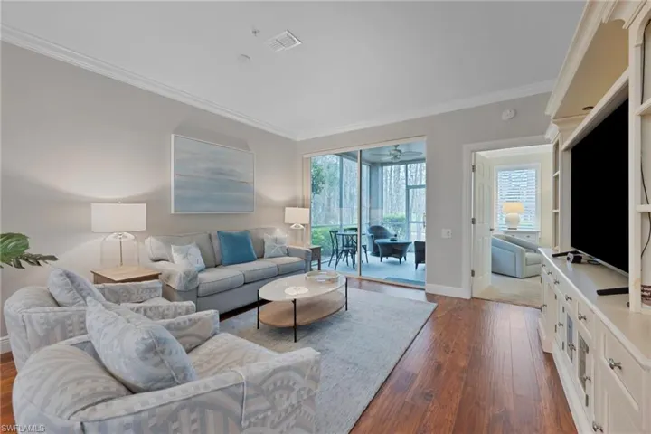 Living area with crown molding, dark wood-style flooring, and a ceiling fan