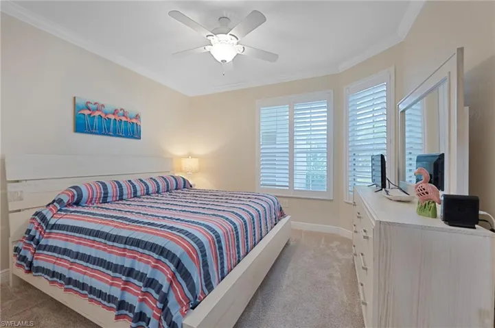 Bedroom featuring ornamental molding, light carpet, and ceiling fan