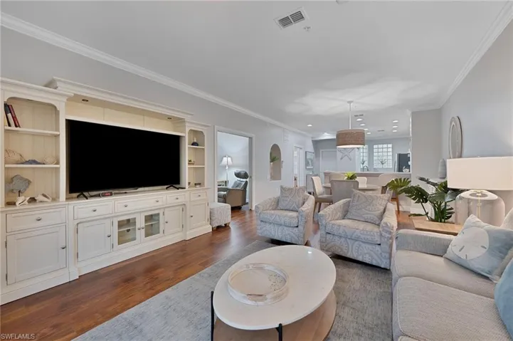 Living area with ornamental molding and dark wood-type flooring