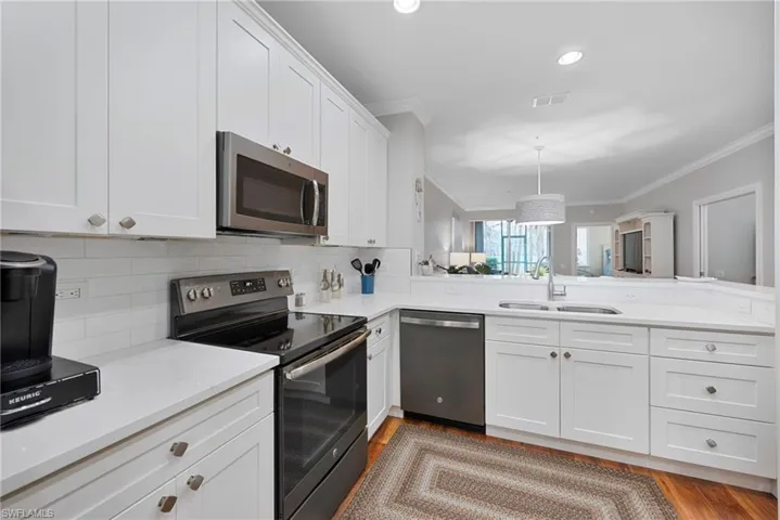Kitchen with stainless steel appliances, crown molding, white cabinets, a peninsula, and recessed lighting