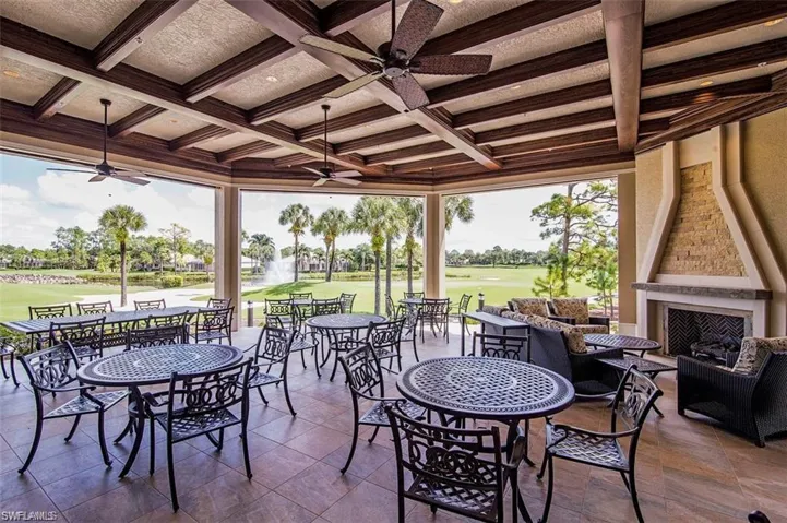 View of patio / terrace featuring view of golf course, outdoor dining area, ceiling fan, and an outdoor living space with a fireplace