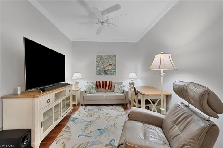Living room featuring crown molding, wood finished floors, and a ceiling fan
