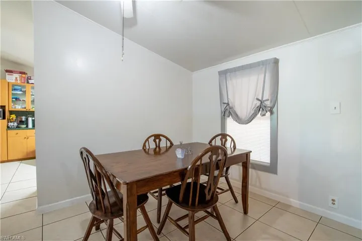 Tiled dining space featuring ornamental molding and lofted ceiling