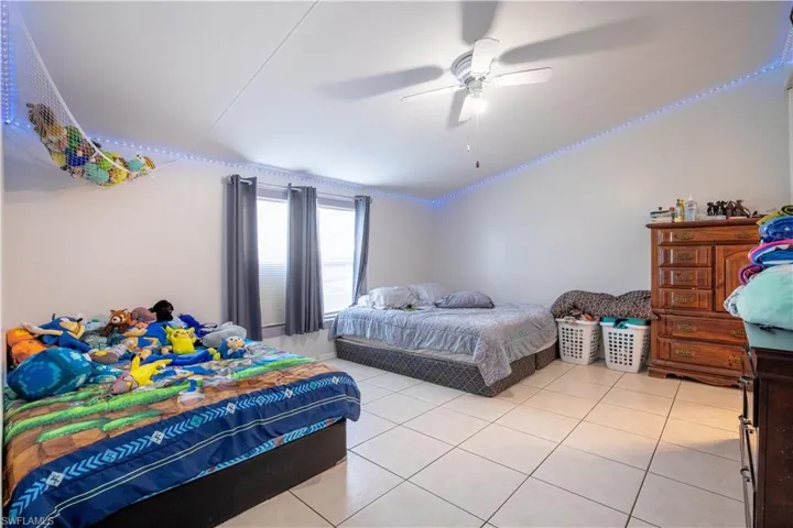 Bedroom with ceiling fan and light tile floors