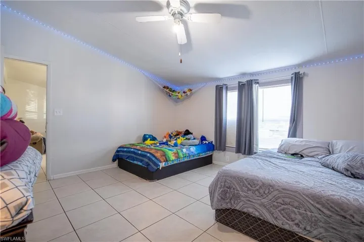 Bedroom with lofted ceiling, ceiling fan, and light tile floors