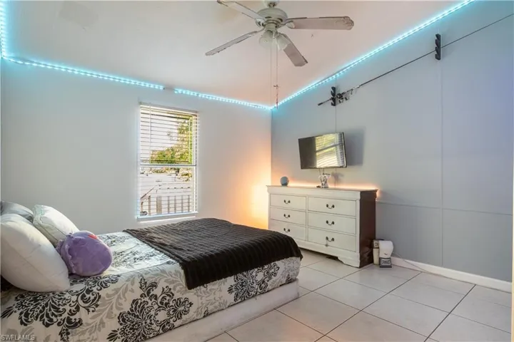 Tiled bedroom featuring ceiling fan and lofted ceiling