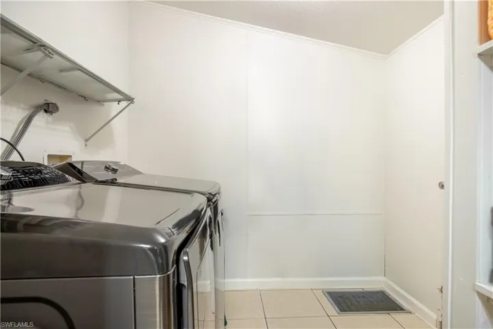 Clothes washing area with separate washer and dryer, washer hookup, light tile floors, and crown molding