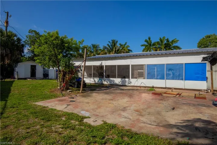Back of house featuring a sunroom, a shed, and a lawn