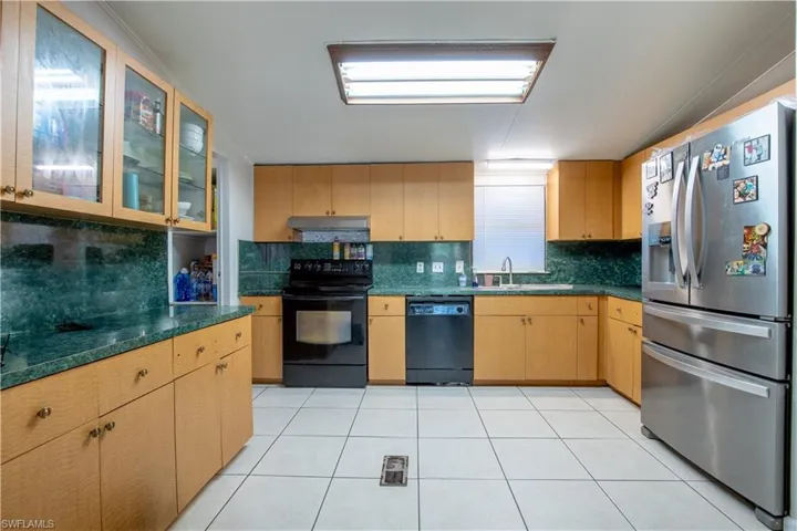 Kitchen featuring black appliances, sink, tasteful backsplash, light tile flooring, and light brown cabinetry