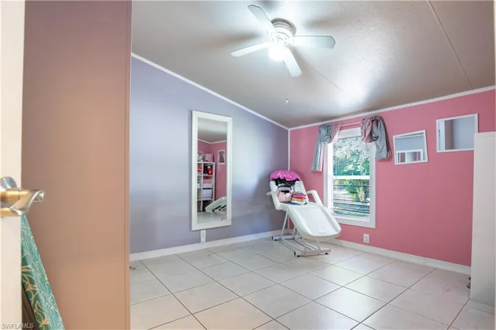 Unfurnished room with ceiling fan, a textured ceiling, tile floors, ornamental molding, and lofted ceiling