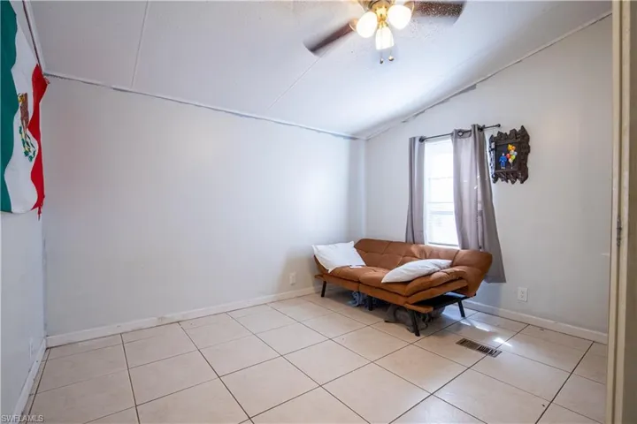 Sitting room featuring ceiling fan, lofted ceiling, and light tile floors