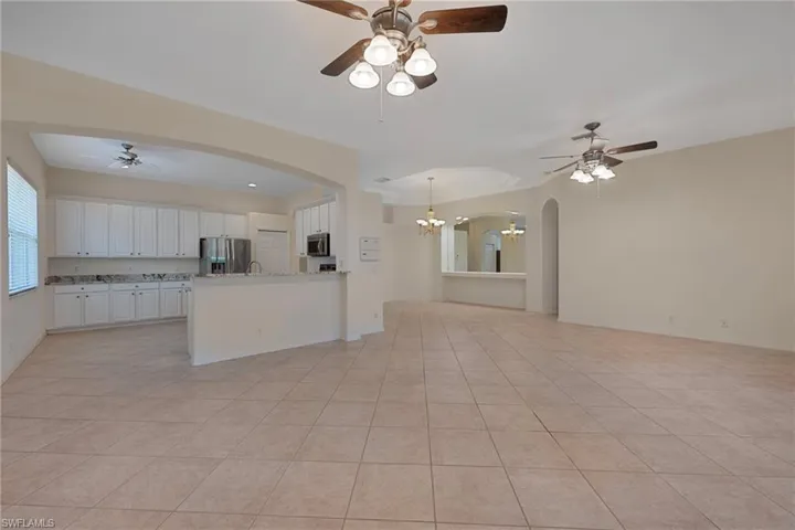 Kitchen featuring a ceiling fan, open floor plan, white cabinetry, and stainless steel appliances