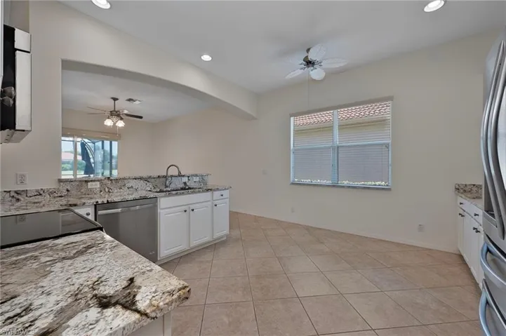 Kitchen featuring a ceiling fan, light stone counters, recessed lighting, stainless steel appliances, and white cabinetry