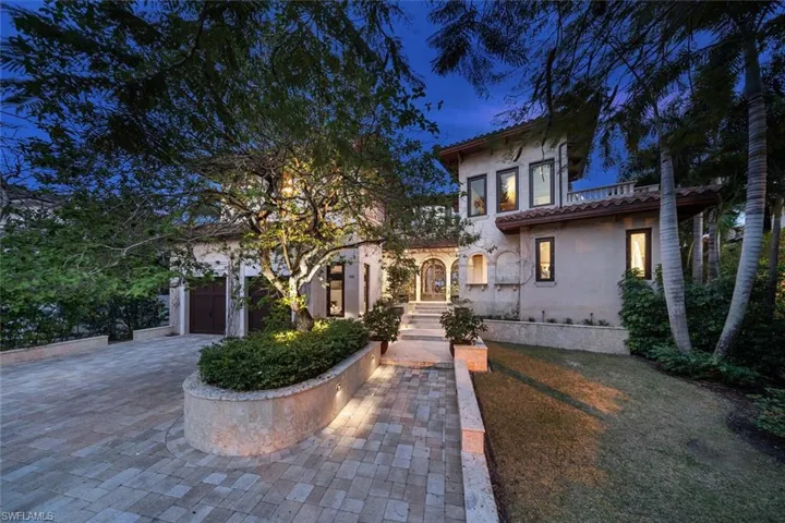 Mediterranean / spanish home featuring stucco siding, decorative driveway, a garage, a front yard, and a tiled roof