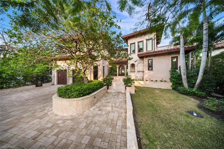 Mediterranean / spanish-style home featuring a front lawn, decorative driveway, stucco siding, a tiled roof, and a garage