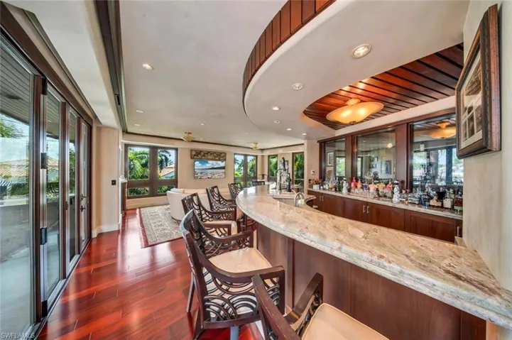 Community bar area featuring light stone counters, dark wood-style floors, and recessed lighting