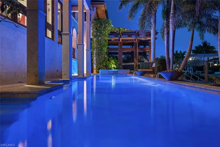 Pool at night with an outdoor pool, a jacuzzi, and a patio area