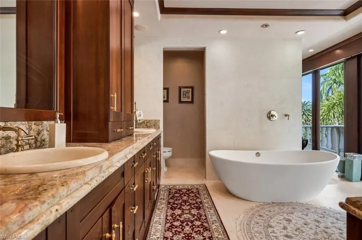 Bathroom with double vanity, a soaking tub, recessed lighting, and light tile patterned flooring