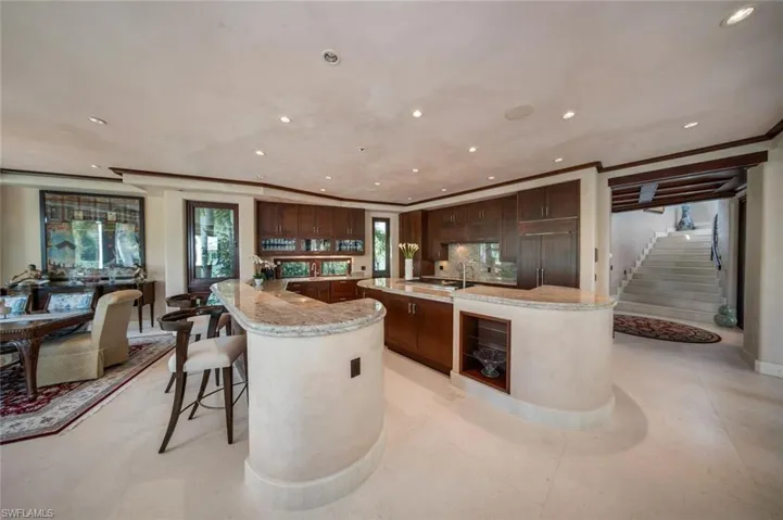 Kitchen with recessed lighting, a kitchen bar, light stone countertops, backsplash, and crown molding
