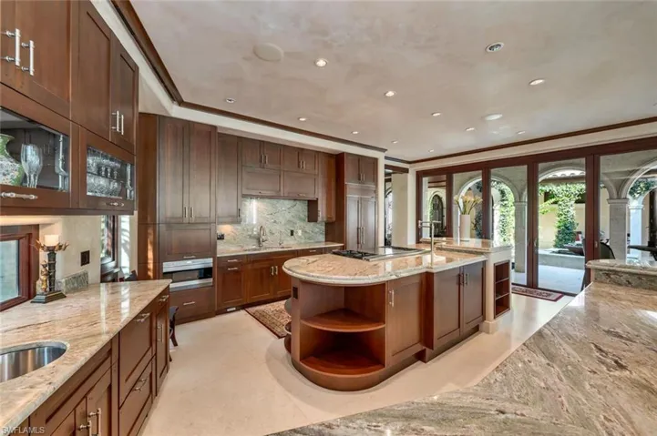 Kitchen featuring open shelves, tasteful backsplash, light stone counters, glass insert cabinets, and recessed lighting