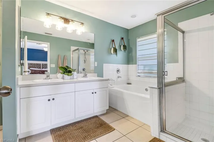 Full bathroom with a stall shower, a garden tub, double vanity, and tile patterned floors