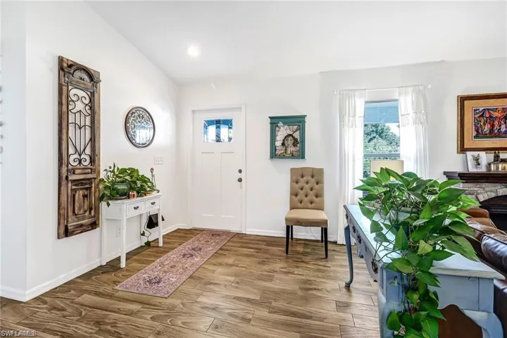 Entryway with healthy amount of natural light, wood finished floors, lofted ceiling, and recessed lighting