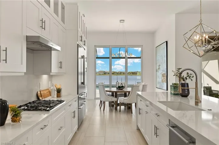 Gourmet Kitchen w/ luxury Thermador appliances, gas cooktop, luxury white cabinetry plus lighted upper cabinets, quartz counters & backsplash w/ oversized waterfall countertop on island, & walk-in pantry w/ frosted glass door