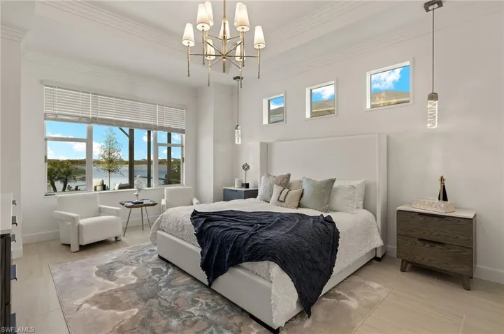 Master Bedroom featuring a tray ceiling, custom crown molding, mounted TV, and an inviting chandelier plus pendant lighting