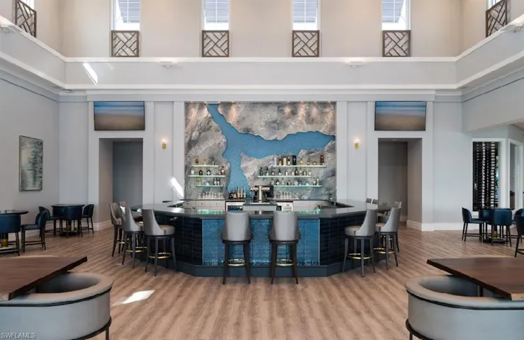 Bar featuring hardwood / wood-style floors, a towering ceiling, and a wealth of natural light