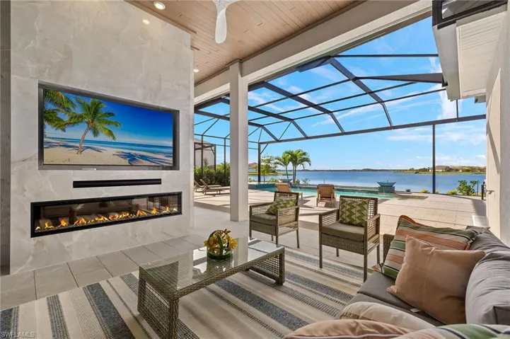 Built-in entertainment center that features an electric fireplace, large format porcelain tile backsplash to ceiling, recessed built-in TV, sound bar, & Faux Wood Ceiling.