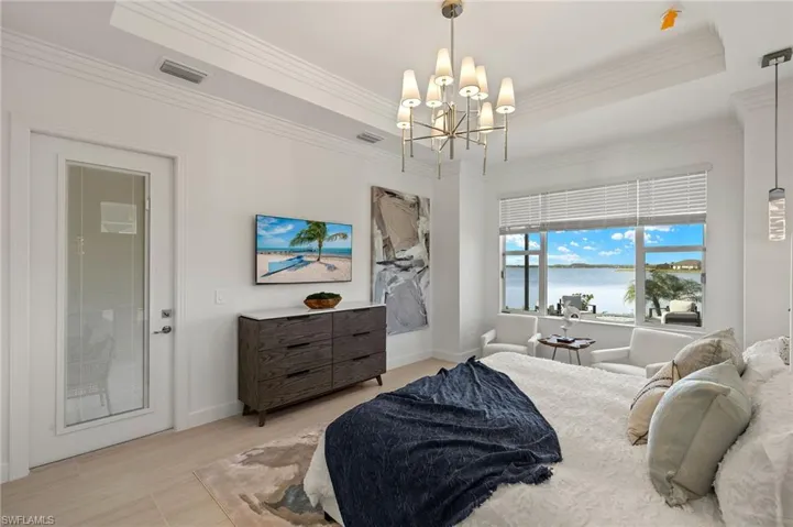 Master Bedroom featuring a tray ceiling, custom crown molding, mounted TV, and an inviting chandelier plus pendant lighting