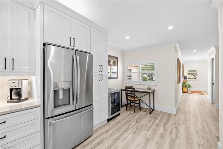 View facing refrigerator, wine cooler, and small desk