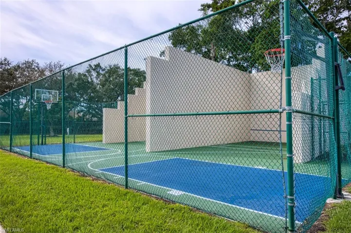 View of basketball court with a lawn, community basketball court, and fence