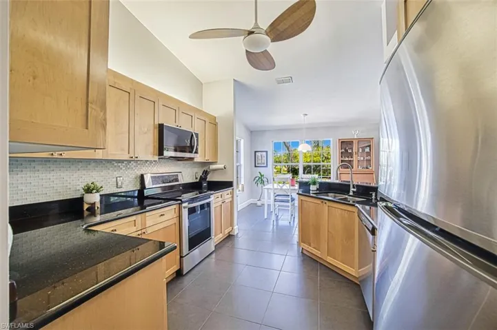 Kitchen with light brown cabinetry, visible vents, stainless steel appliances, and decorative backsplash