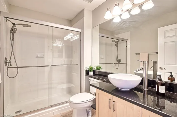 Bathroom with vanity, a shower stall, toilet, and tile patterned floors