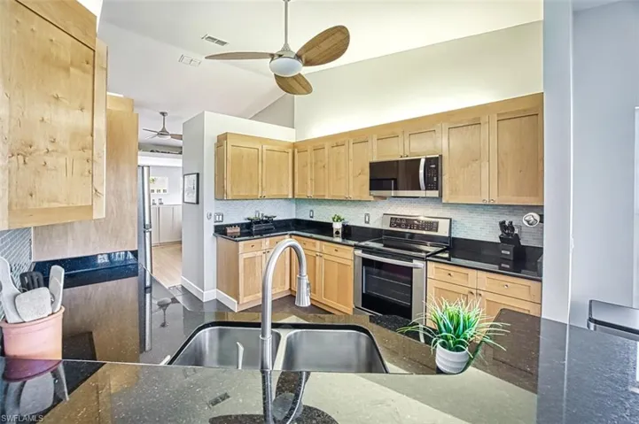 Kitchen with light brown cabinets, appliances with stainless steel finishes, and a sink