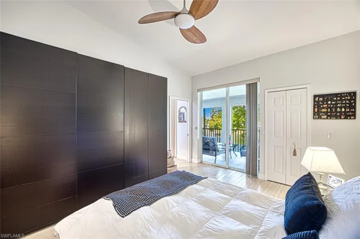 Bedroom with light wood finished floors, vaulted ceiling, a ceiling fan, and access to outside