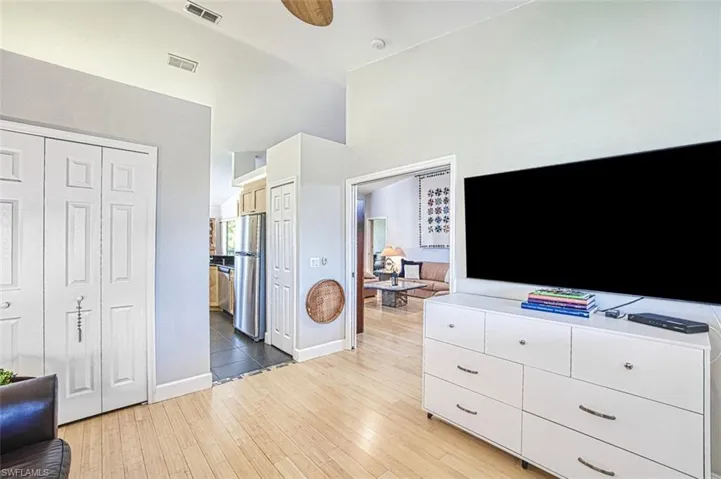 Bedroom with visible vents, light wood finished floors, baseboards, and freestanding refrigerator