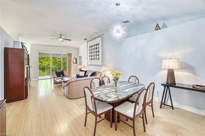Dining space featuring visible vents, baseboards, lofted ceiling, light wood-style flooring, and a ceiling fan