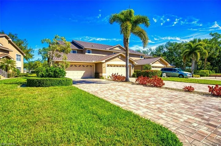 View of front of home with a front yard, stucco siding, a garage, a tile roof, and decorative driveway