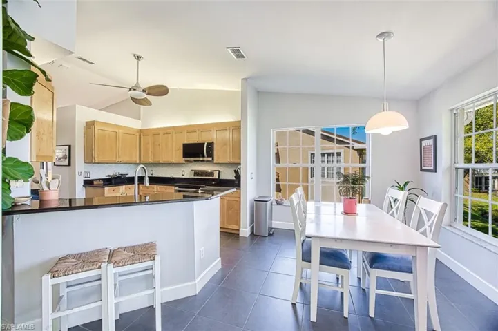 Kitchen with dark countertops, appliances with stainless steel finishes, lofted ceiling, and light brown cabinetry