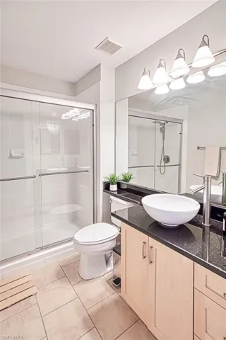 Full bathroom featuring tile patterned flooring, visible vents, a shower stall, toilet, and vanity